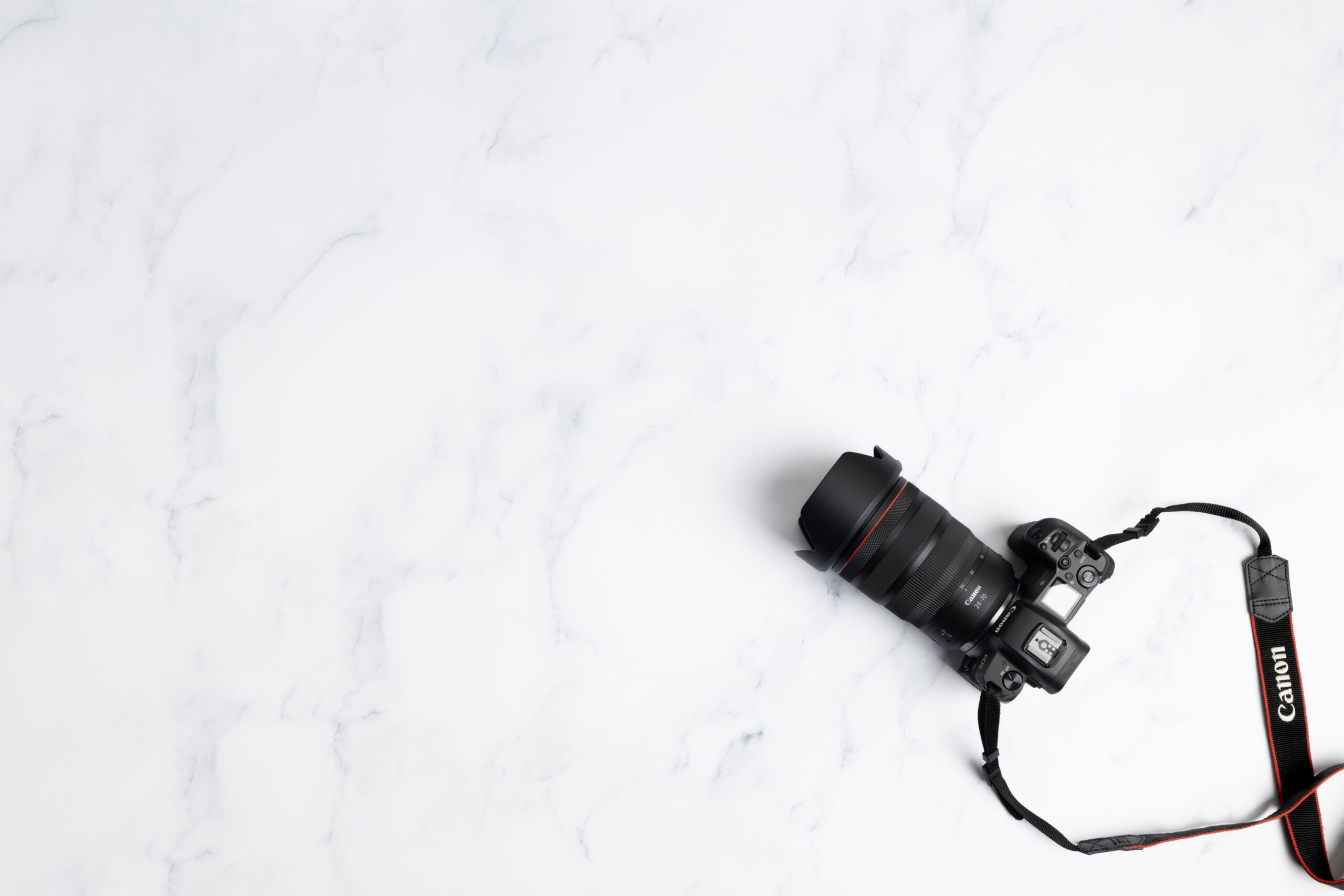 A professional dslr camera equipped with a large lens, resting on a sleek white marble surface with plenty of copy space.