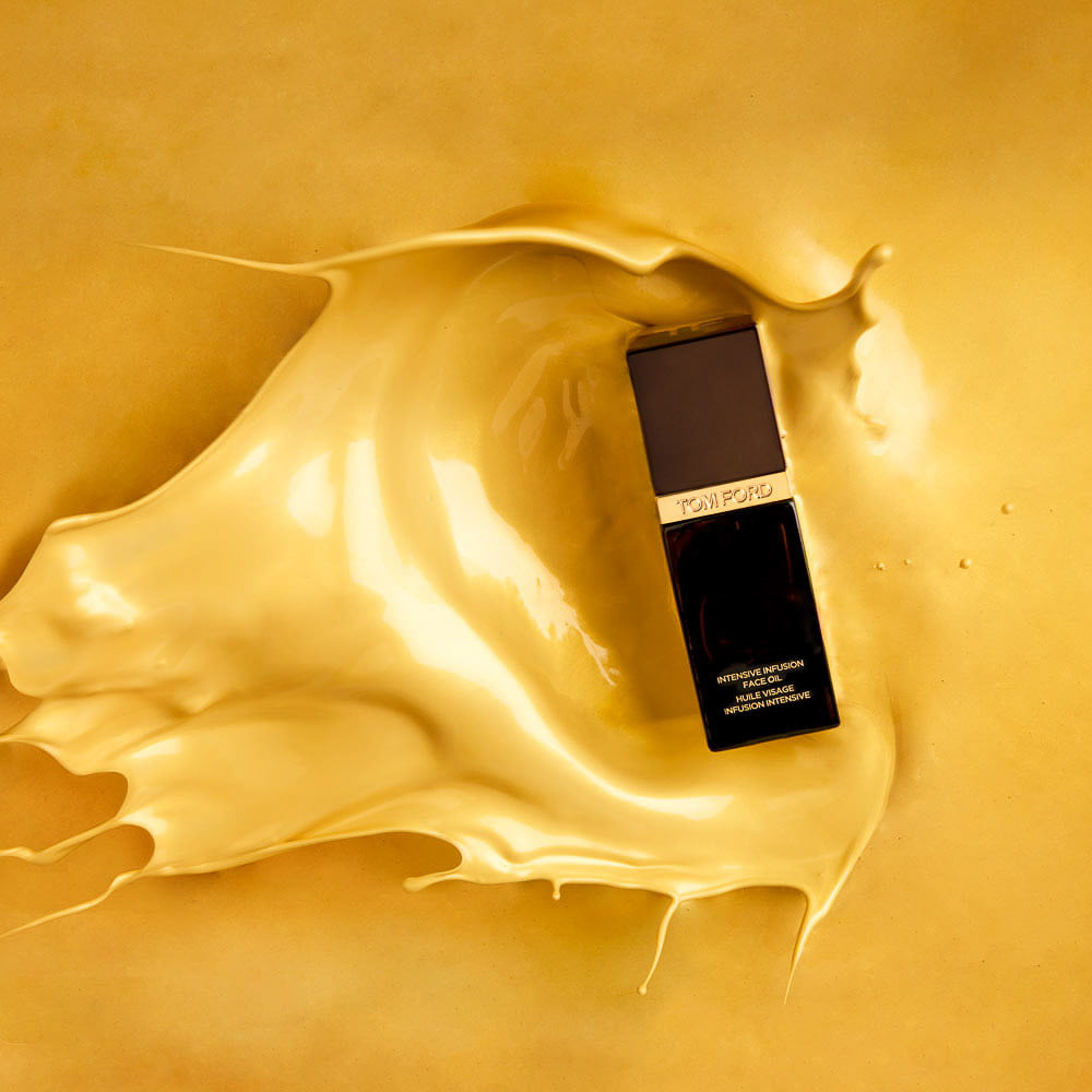 A bottle of Tom Ford foundation immersed in a luxurious splash of its own creamy, beige liquid makeup on a golden background, captured in stunning product photography.
